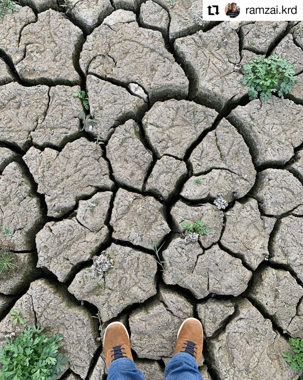 dried out earth with a pair of feet standing on it